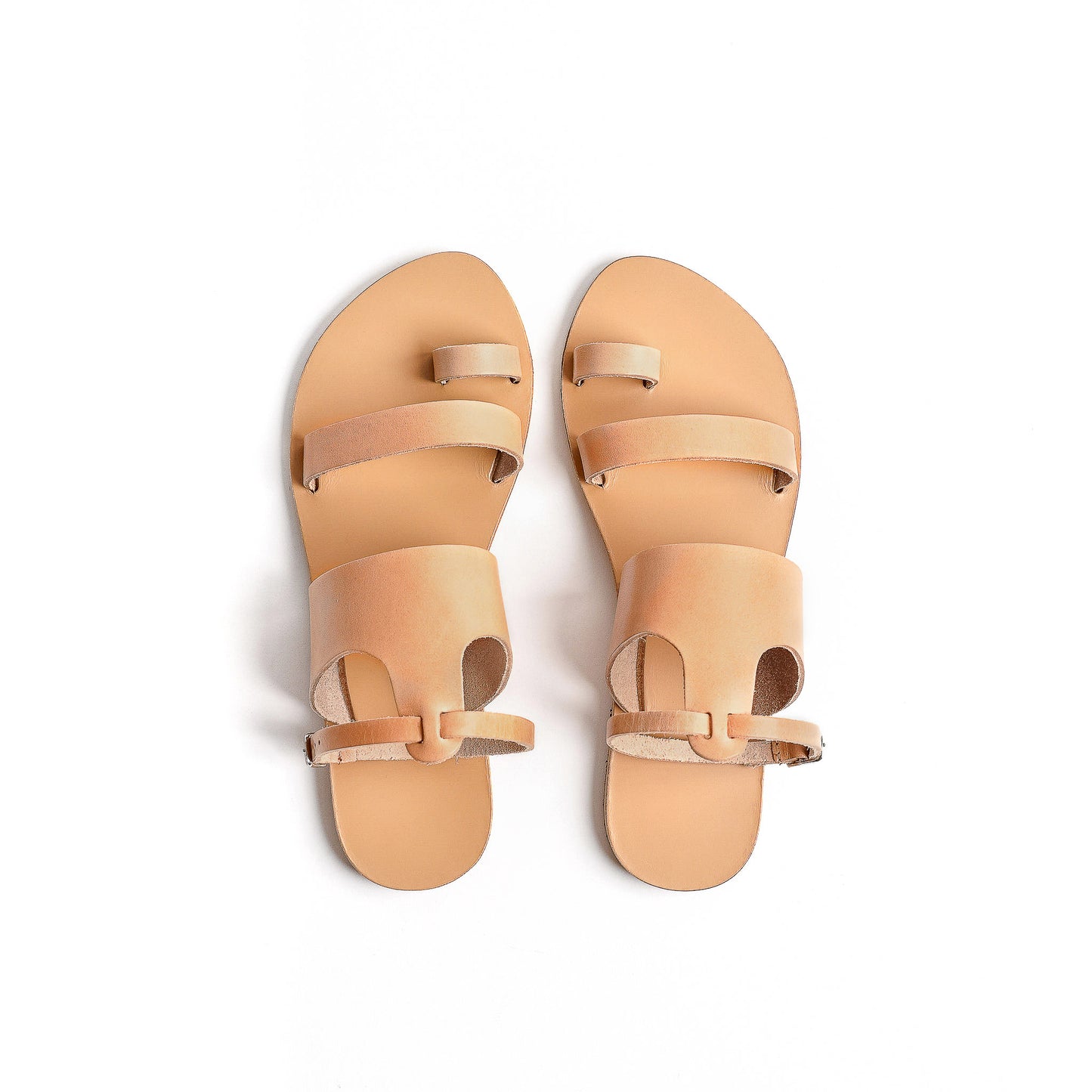 Top view of tan flat sandals with strap for women against a white background. They are flat sandals with ankle strap.