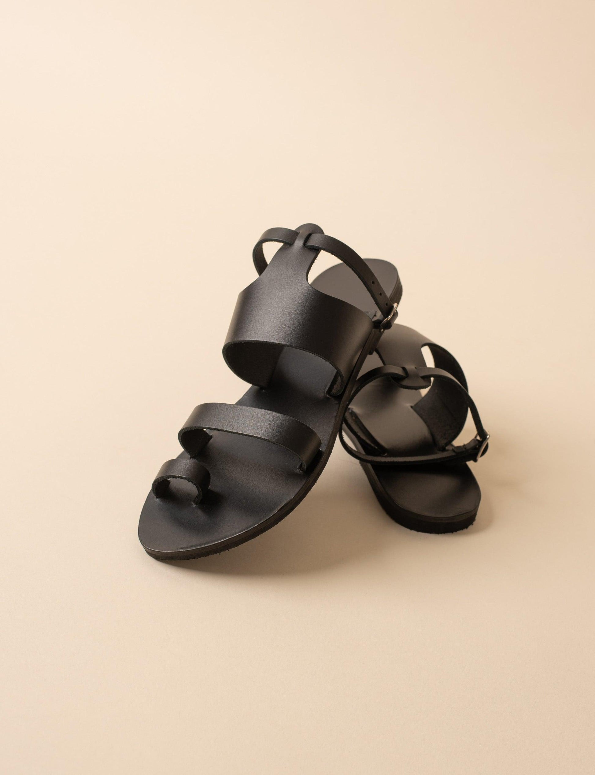 Alexandra womens flats in black leather against a beige background. They are black flats with ankle strap.