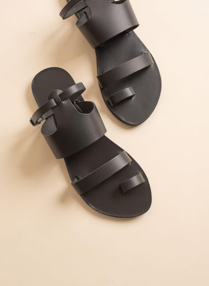 Top view of Alexandra womens flats in black against a beige background. They are black flats with ankle strap.