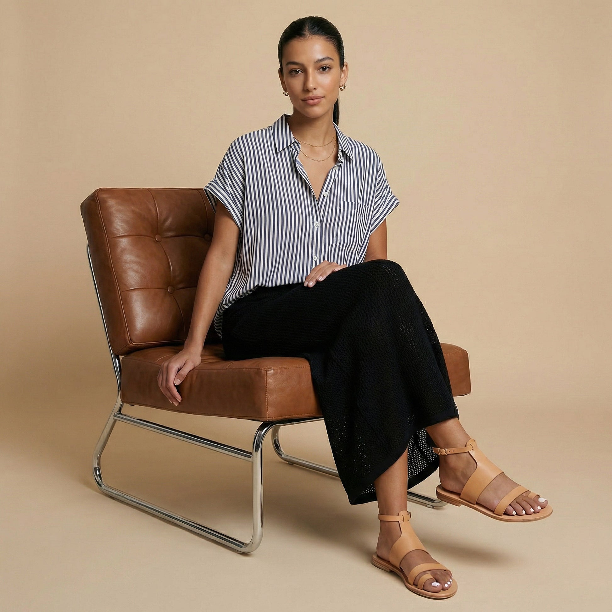 Woman wearing a pair of tan flat sandals with strap for women against a white background. They are flat sandals with ankle strap.