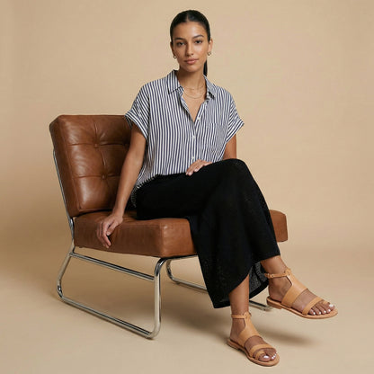 Woman wearing a pair of tan flat sandals with strap for women against a white background. They are flat sandals with ankle strap.
