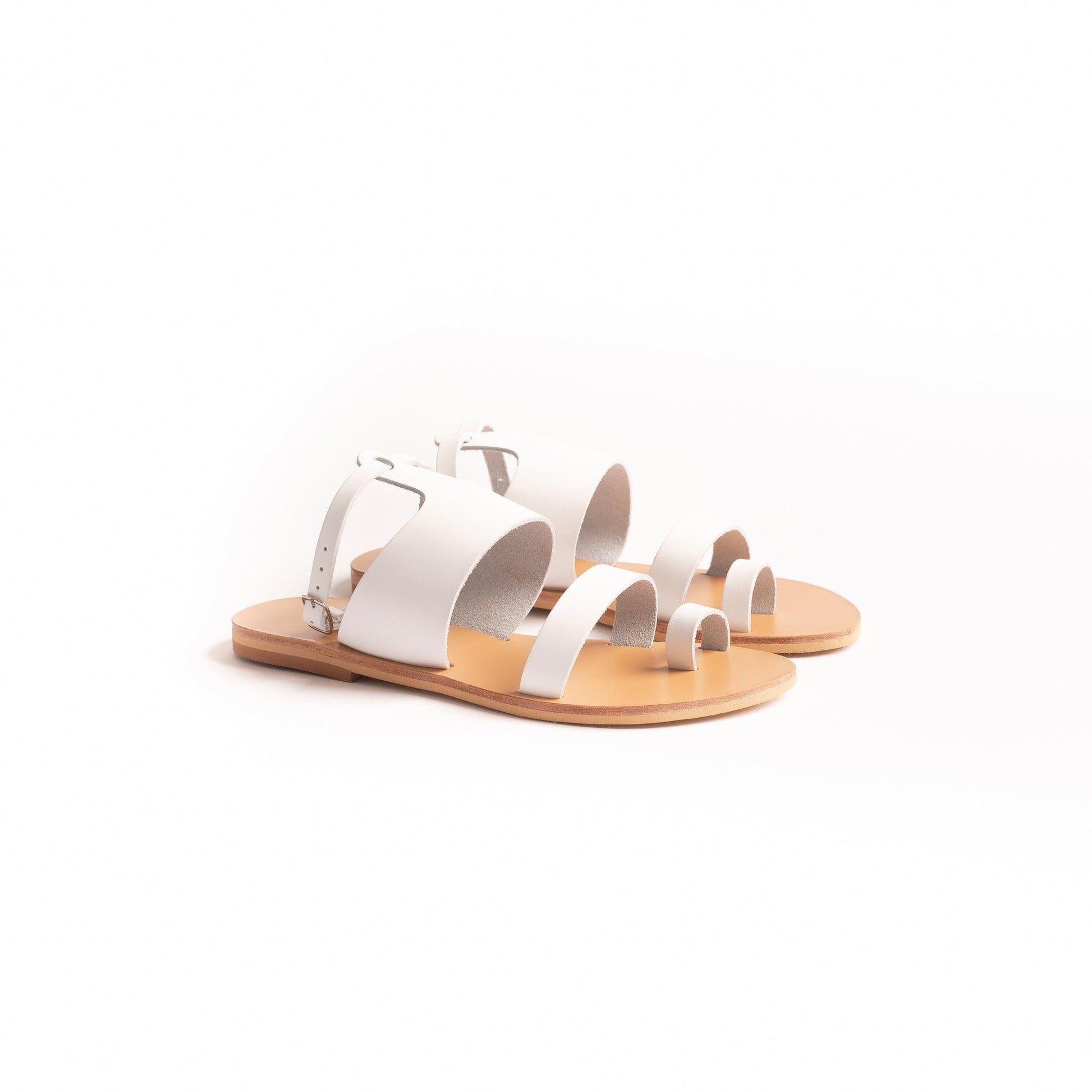 side view of white flat sandals against a white background. They are white ankle strap sandals.