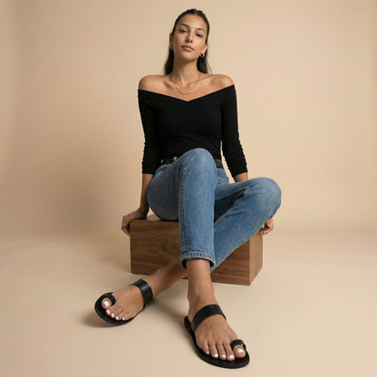 Woman wearing Astara ladies black flats against a beige background.