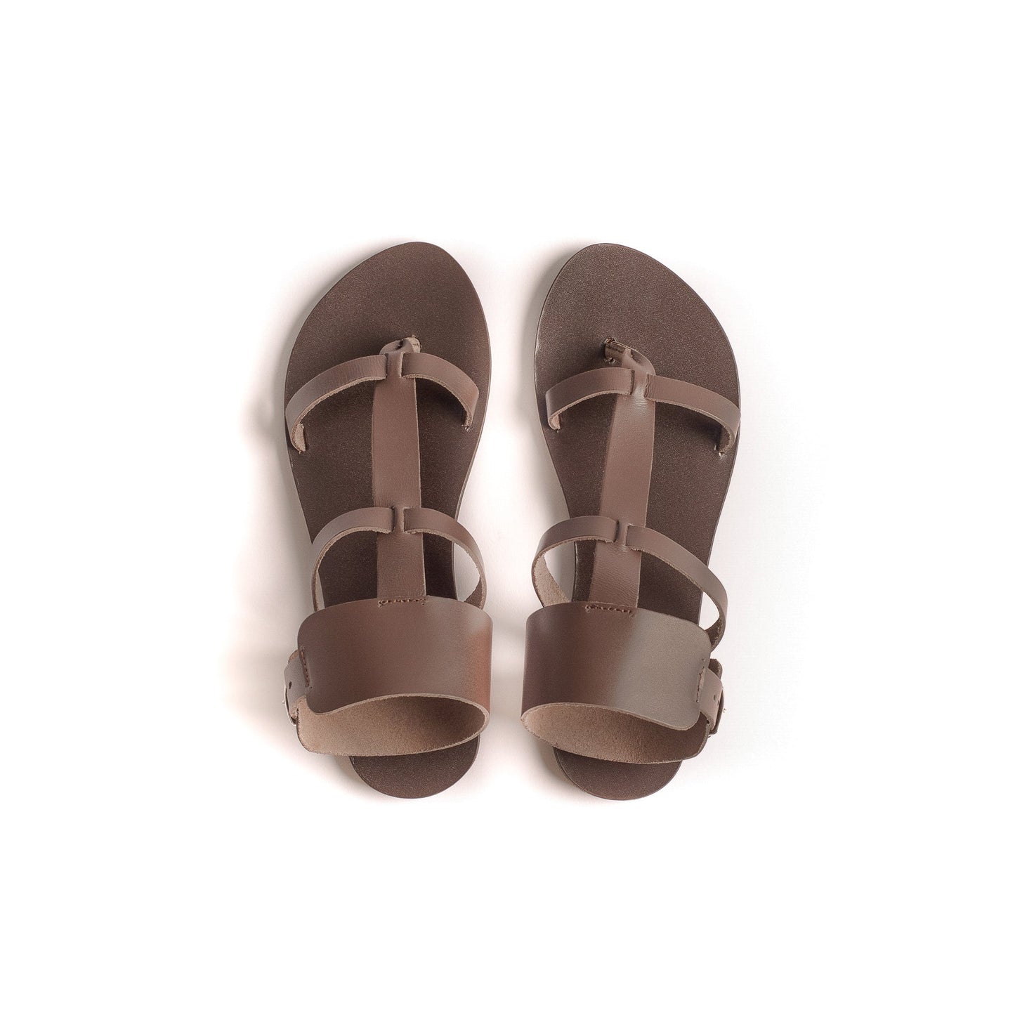 Top view of Athena brown flats against a white background. They are flat sandals with buckle.