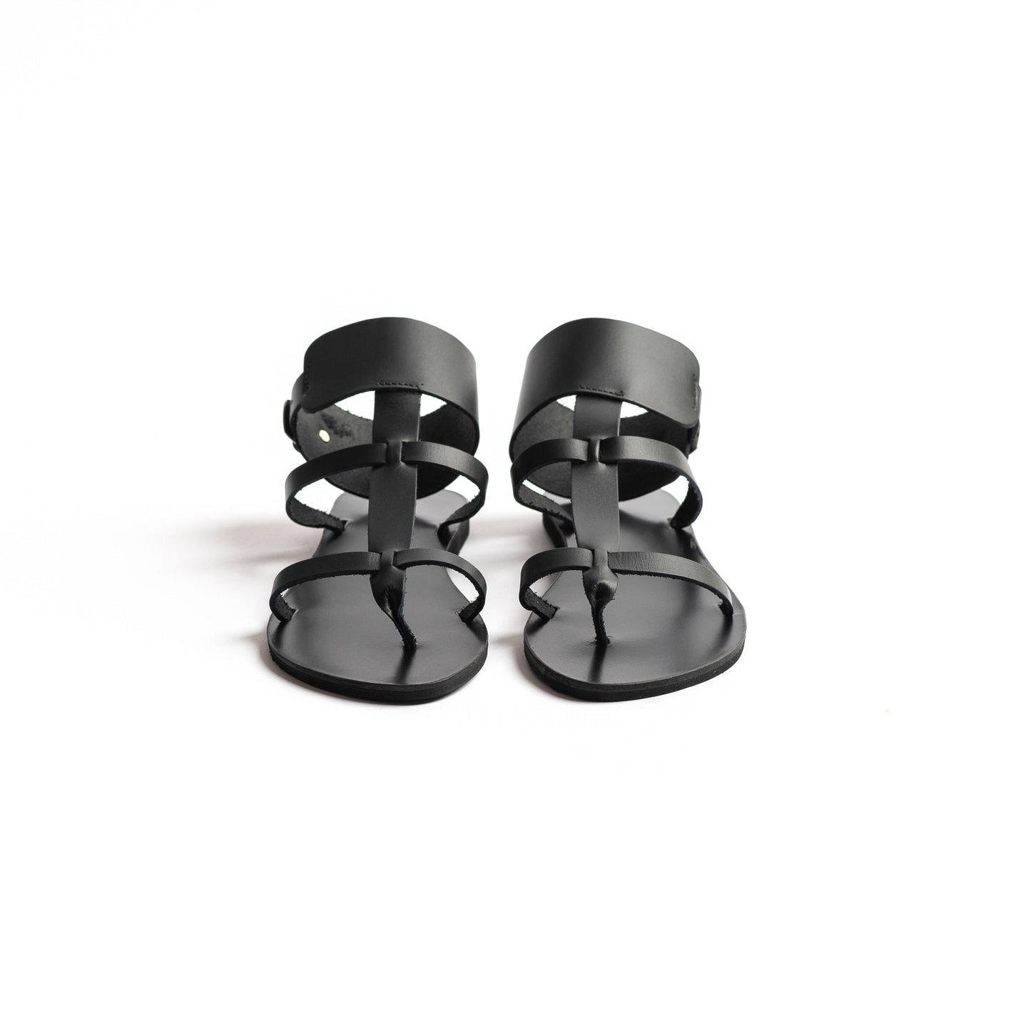 Front view of Athena black leather sandals in black against a white background. They  are black flat gladiator sandals.