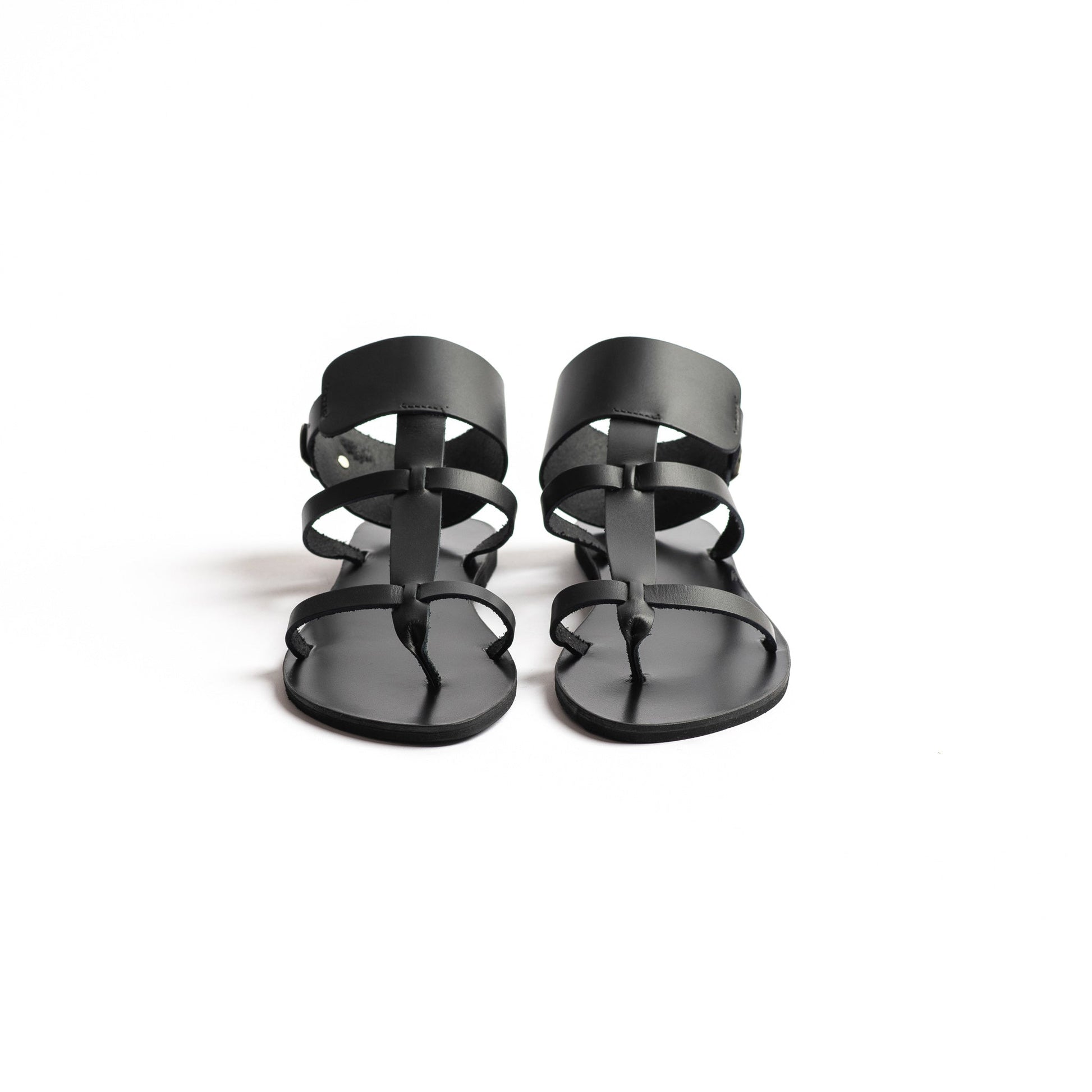 Front view of Athena black leather sandals in black against a white background. They  are black flat gladiator sandals.