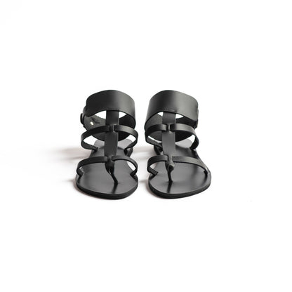 Front view of Athena black leather sandals in black against a white background. They  are black flat gladiator sandals.