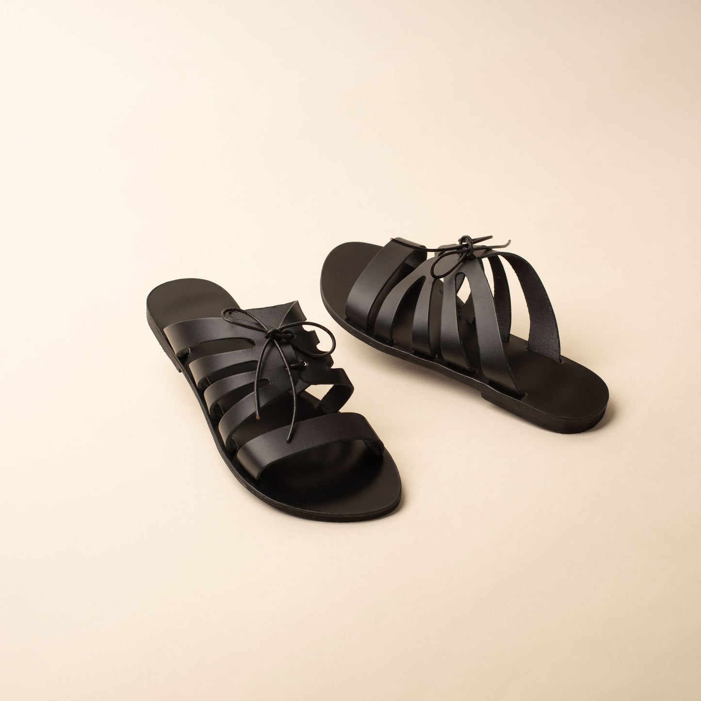 Pair of black flats with bow against a beige background. These are flat slippers for womens / flat slippers for ladies.