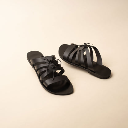 Pair of black flats with bow against a beige background. These are flat slippers for womens / flat slippers for ladies.