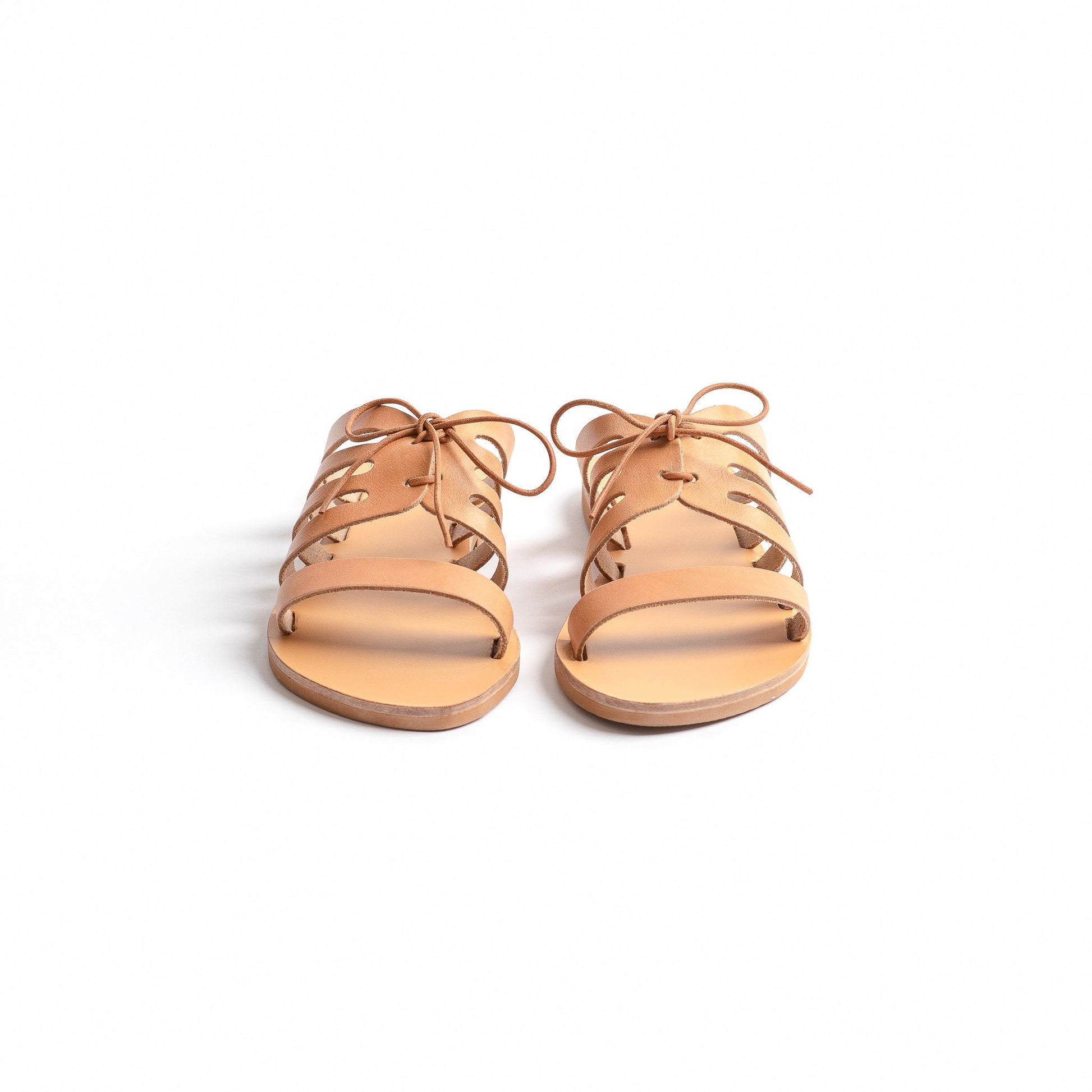 Chloe comfortable flats in the natural color shot from the front against a white background. They are a pair of bow sandals flat.