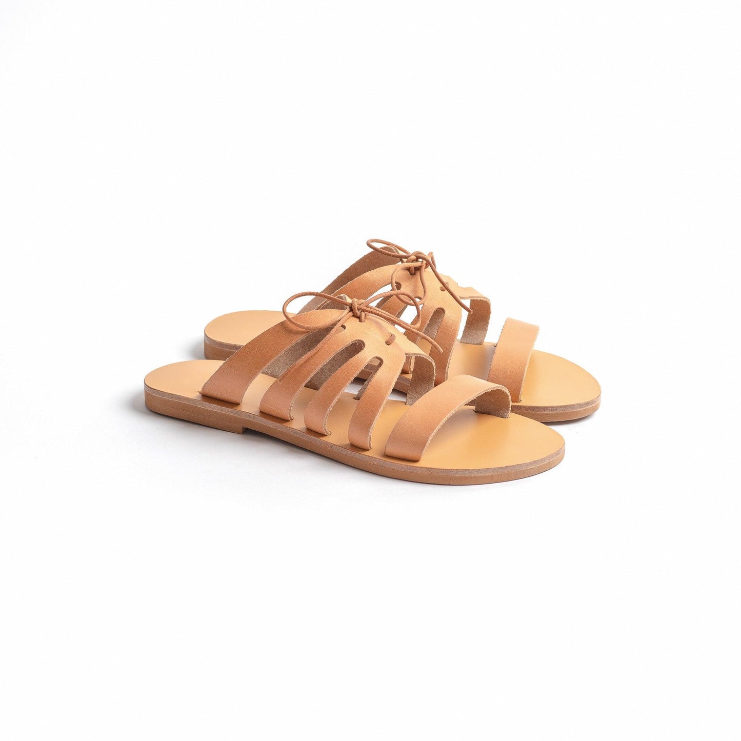 Side view of tan comfortable flats with against a white background. They are a pair of bow sandals flat.