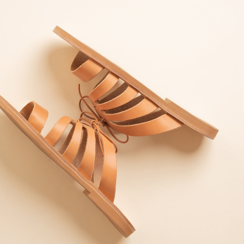 Pair of Tan Leather Sandals for Women Against a Beige Background