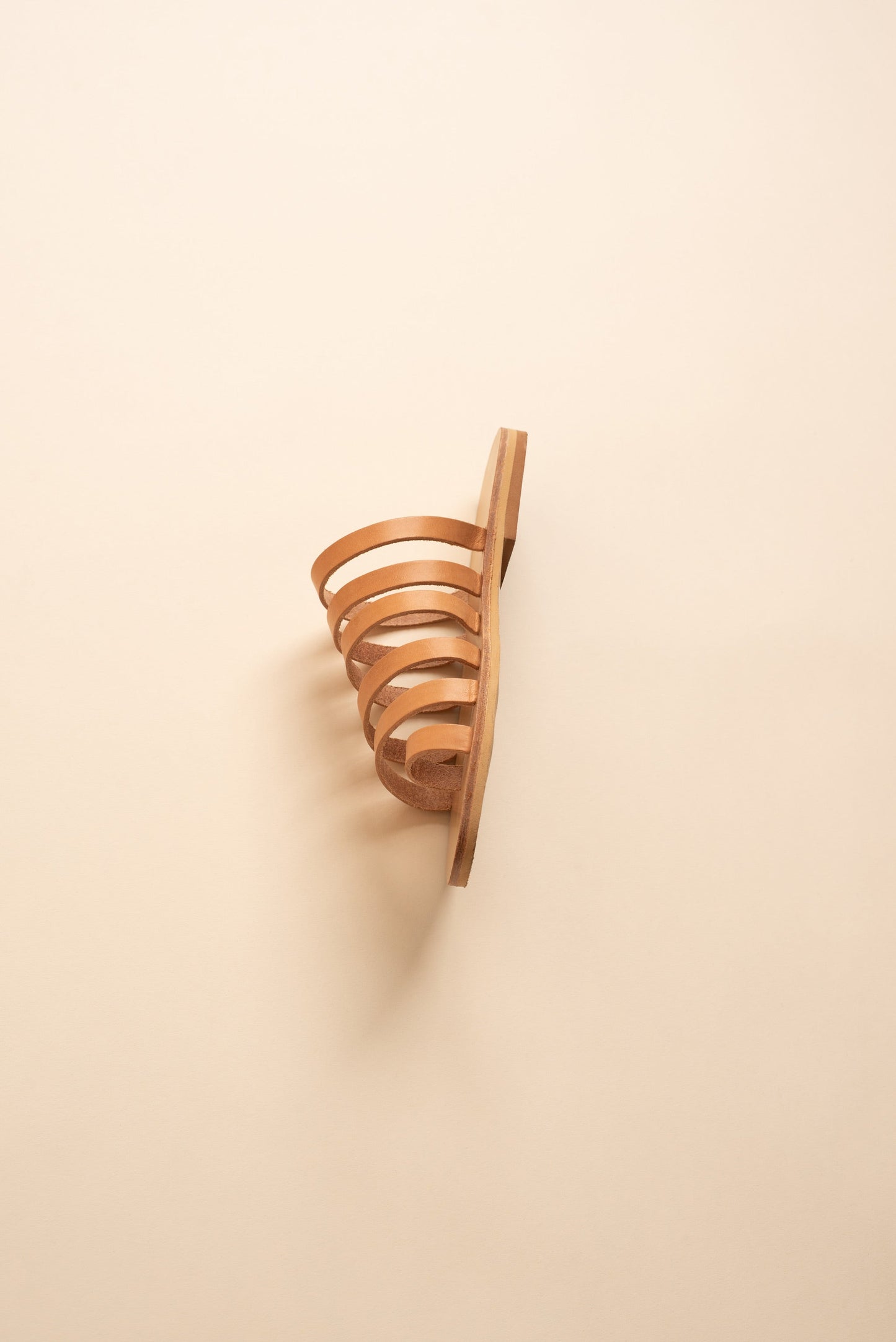 Harmonia flat sandals open toe in tan against a beige background. These are flat sandals without back strap.
