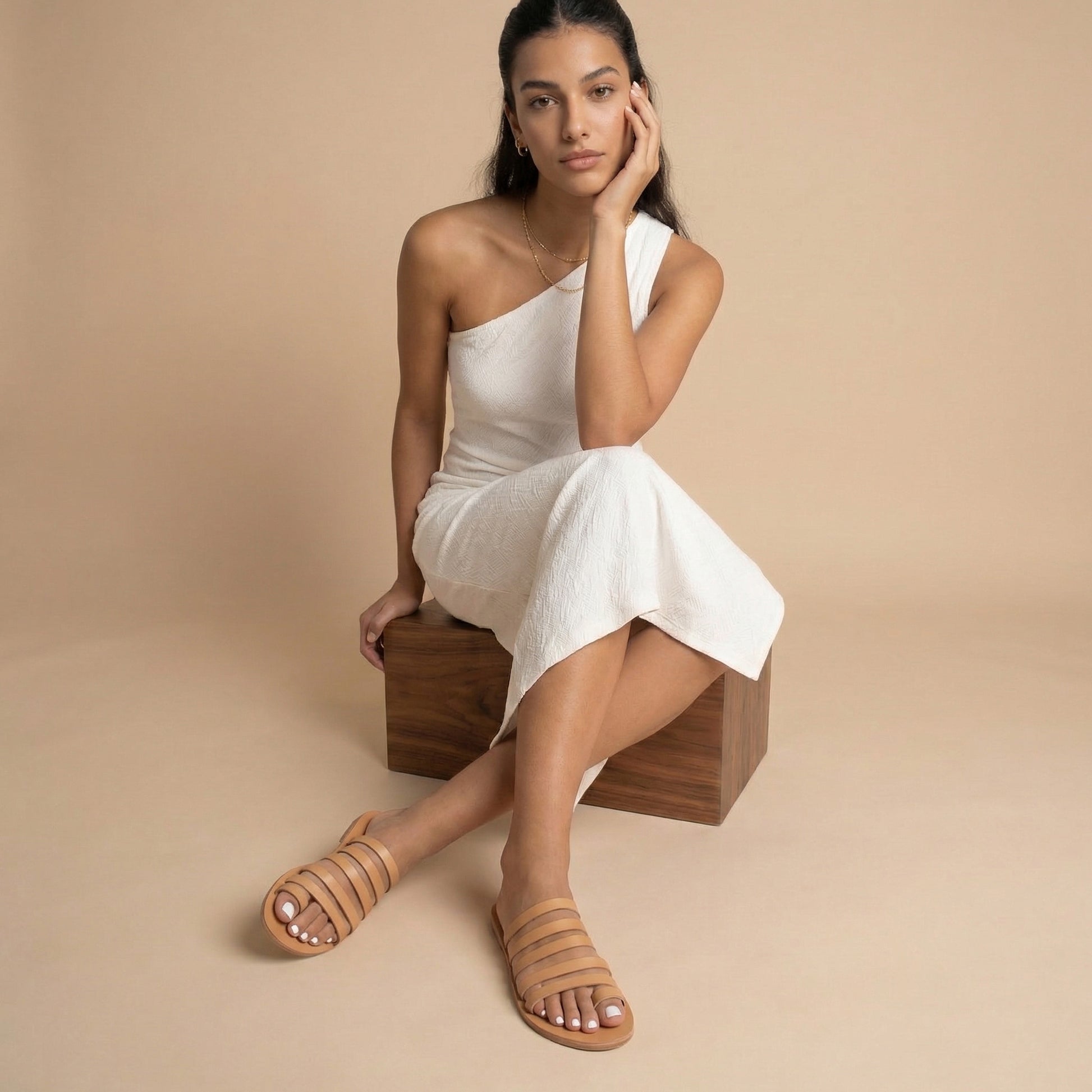 Woman wearing Harmonia flat sandals open toe against a beige background. These are flat sandals without back strap.