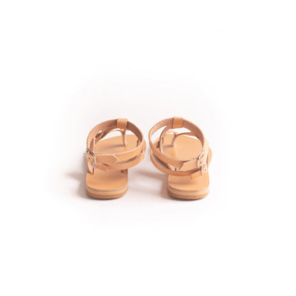 Back view of flat sandals designer in camel against a white background. They are women's flats with ankle straps.