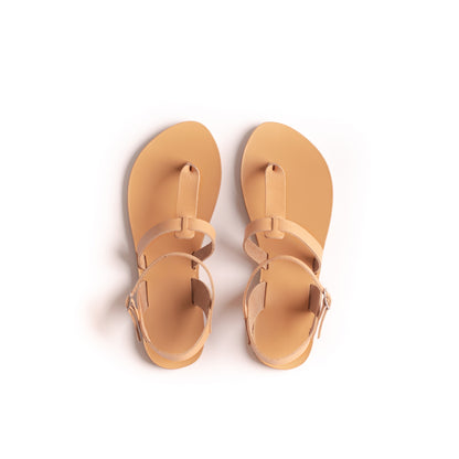 Top view of a pair of tan flat sandals one strap on a white background. They are flat sandals beige.