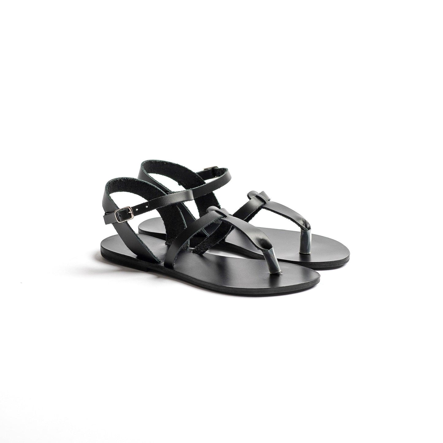 Pair of black designer flat sandals on a white background. They are flat sandals one strap.