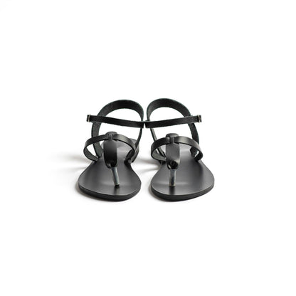 Front view of a pair of black designer flat sandals ankle strap on a white background. They are flat sandals t strap.