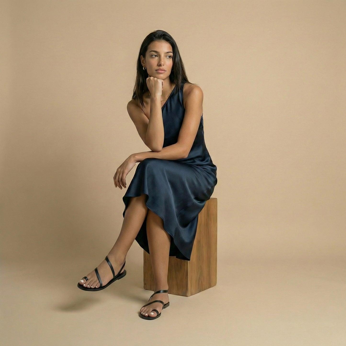 A woman wearing flat sandals black next to a potted plant with pink flowers on a stone pavement. They are fancy black flats.